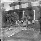 African American men with horse-drawn buckboard in front of a house